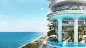 DAMAC Casa ocean-view sky pool terrace featuring sculptural waterfall columns, curved glass balconies, and lush tropical landscaping overlooking the Gulf coastline in Dubai. Presented by Tohid Fetrat.