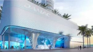 DAMAC Casa podium entrance featuring a sculpted architectural façade with illuminated patterns, double-height retail and lobby spaces, and contemporary waterfront design in Dubai. Presented by Tohid Fetrat.