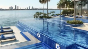 Waterfront infinity pool at DAMAC Chelsea Residences Blue Beach Club featuring blue tiled edges, palm lined deck, sun loungers, and open views across the Gulf in Dubai, Presented by Tohid Fetrat
