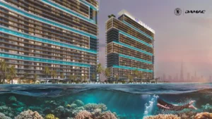 Oceanfront view of DAMAC Chelsea Residences towers rising above clear waters with a visible coral reef below, blending contemporary architecture with a coastal setting in Dubai, Presented by Tohid Fetrat