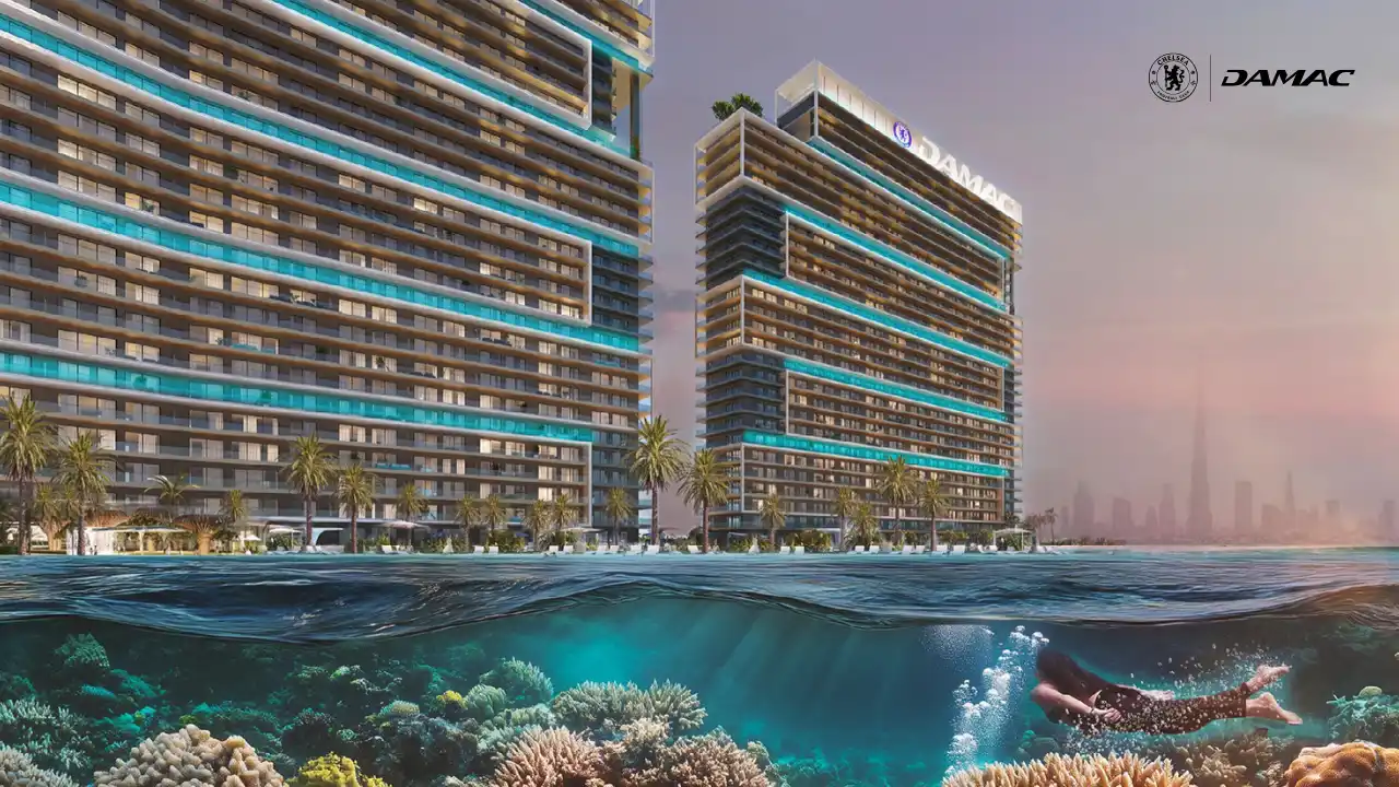 Oceanfront view of DAMAC Chelsea Residences towers rising above clear waters with a visible coral reef below, blending contemporary architecture with a coastal setting in Dubai, Presented by Tohid Fetrat