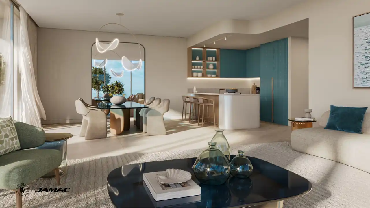 Open plan dining and kitchen interior at DAMAC Chelsea Residences featuring a sculptural dining table, soft contemporary seating, an island kitchen with bar stools, and calm natural tones in Dubai, Presented by Tohid Fetrat