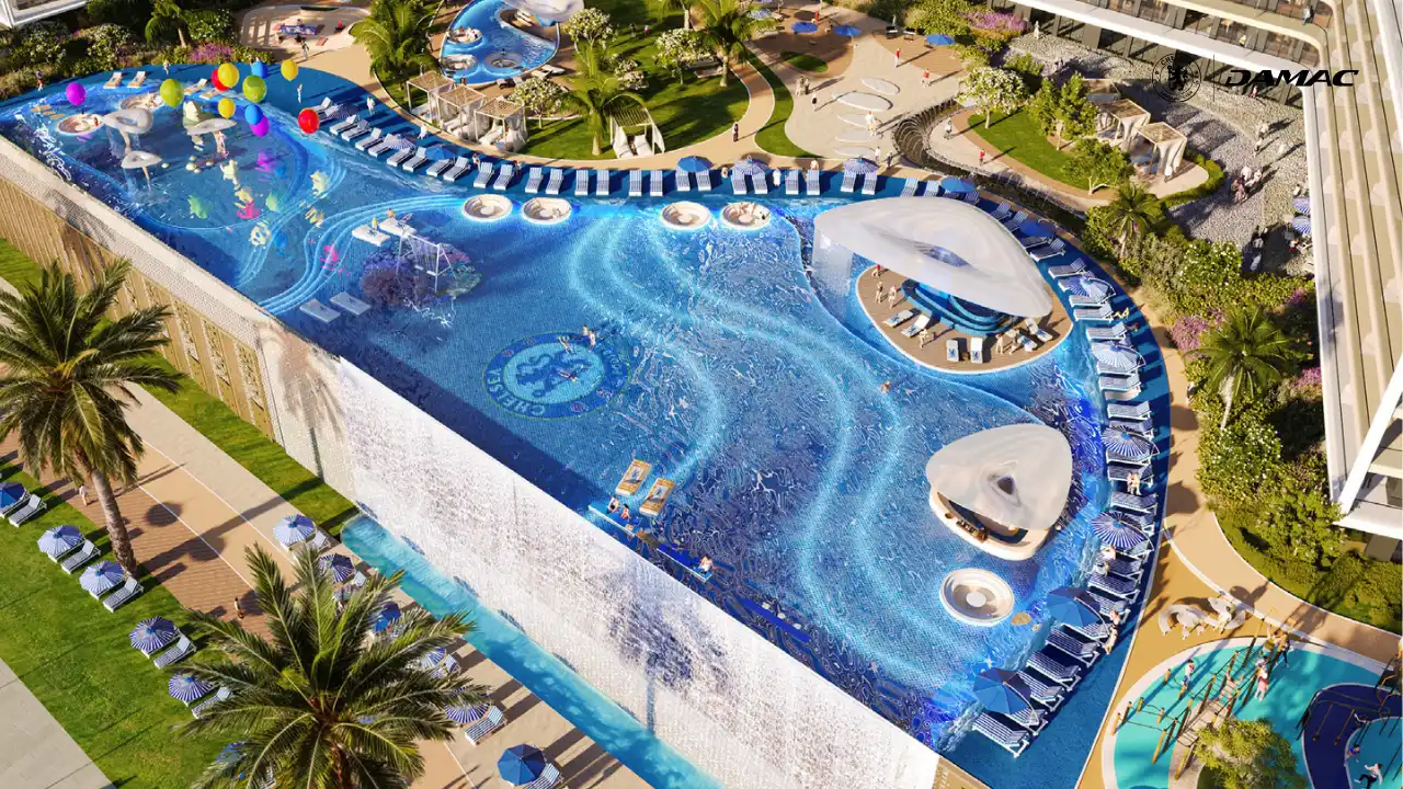 Aerial view of the elevated pool at DAMAC Chelsea Residences Lion Beach featuring a cascading waterfall edge, blue themed design, sun loungers, and landscaped leisure decks in Dubai, Presented by Tohid Fetrat