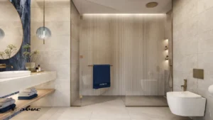 Interior view of the master bathroom at DAMAC Chelsea Residences featuring a walk in glass shower, refined stone finishes, modern vanity, and warm ambient lighting in Dubai, Presented by Tohid Fetrat