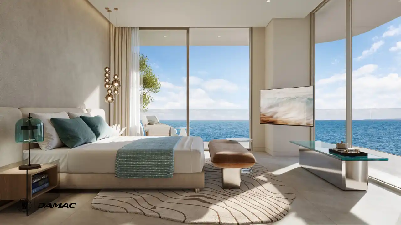 Interior view of the master bedroom at DAMAC Chelsea Residences featuring a serene bed setting, soft neutral tones, floor to ceiling windows, and uninterrupted ocean views in Dubai, Presented by Tohid Fetrat