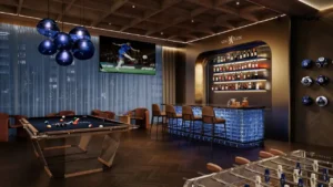 Interior view of the Powerhouse Lounge at DAMAC Chelsea Residences featuring a refined bar, billiards table, foosball area, ambient lighting, and Chelsea themed design elements in Dubai, Presented by Tohid Fetrat