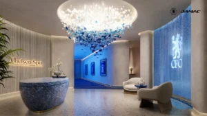 Interior view of the Serenity Spa athlete treatment area at DAMAC Chelsea Residences featuring a sculptural chandelier installation, refined reception desk, ambient blue lighting, and Chelsea branded spa design in Dubai, Presented by Tohid Fetrat