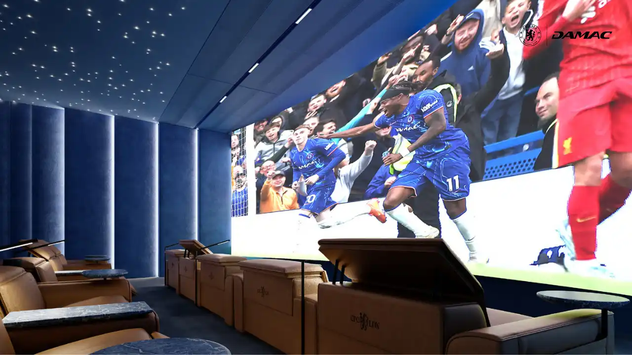 Interior view of the Stamford Cinema Pride Lounge at DAMAC Chelsea Residences featuring luxury recliner seating, immersive large screen display, ambient blue lighting, and a premium private cinema atmosphere in Dubai, Presented by Tohid Fetrat