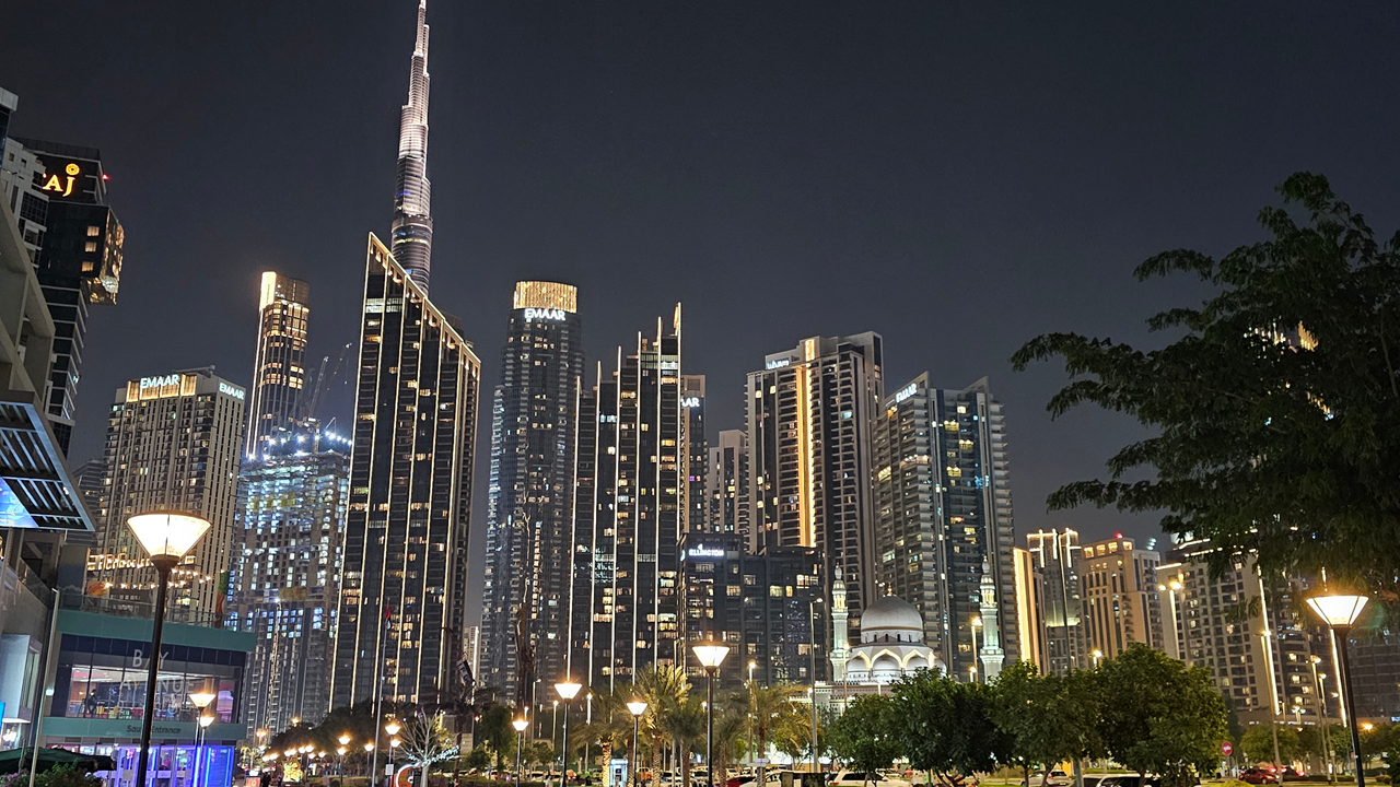 Night skyline view of Downtown Dubai featuring Burj Khalifa, surrounding residential towers, landscaped public spaces, and illuminated urban infrastructure, representing the regulated real estate environment where escrow accounts protect property buyers. Presented by Tohid Fetrat.