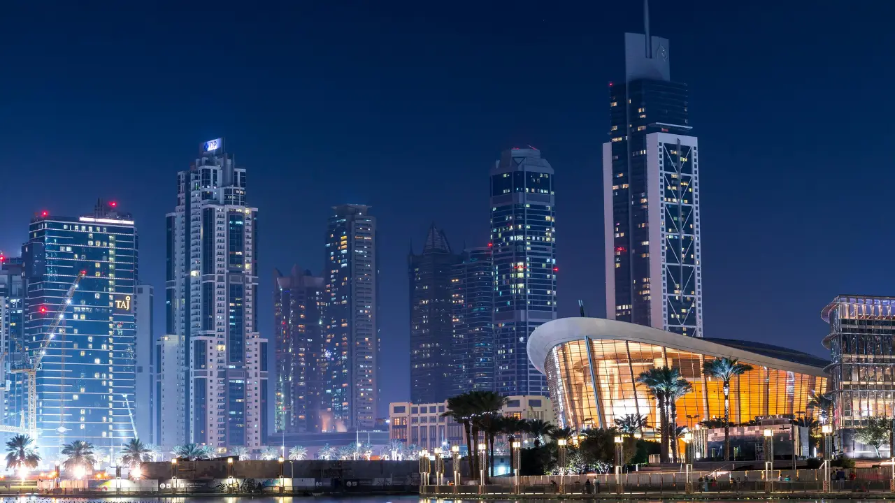 Night view of Dubai skyline featuring illuminated high rise towers and modern waterfront architecture, representing the official government fees associated with the UAE Golden Visa application process in Dubai. Presented by Tohid Fetrat.