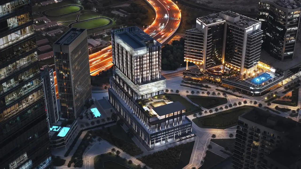Aerial night view of Haus of Tenet in Dubai showcasing illuminated architecture, surrounding towers, and flowing highway lights in Business Bay, presented by Tohid Fetrat