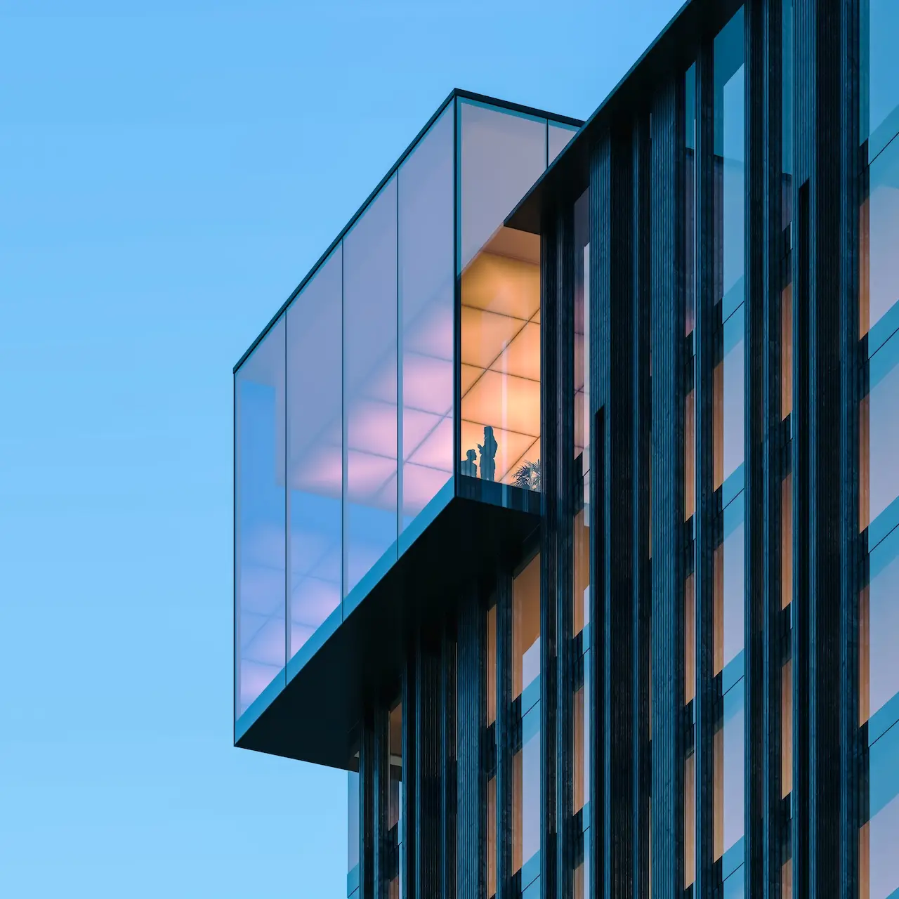Crown architectural detail of Haus of Tenet by IRTH featuring a glass-enclosed upper level with illuminated interiors, showcasing modern design in Business Bay, Dubai, presented by Tohid Fetrat