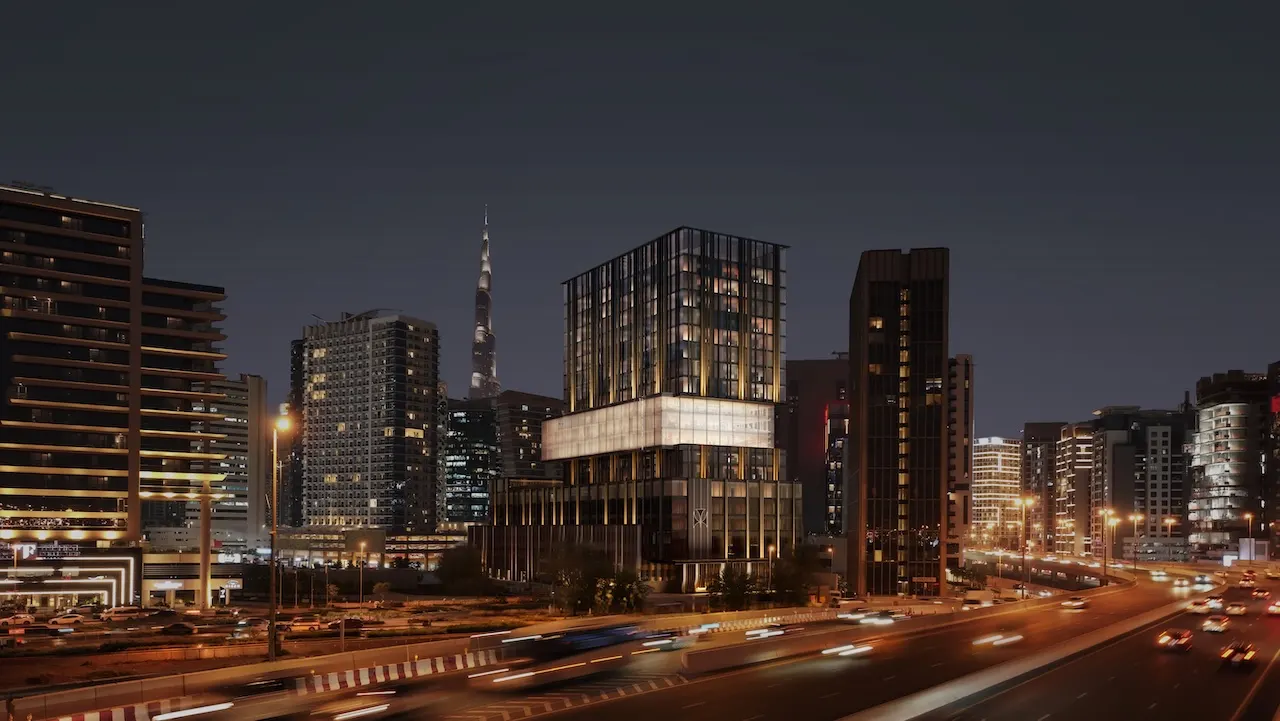 Night exterior view of Haus of Tenet by IRTH in Business Bay, Dubai, featuring illuminated architecture with Burj Khalifa skyline backdrop and major road connectivity, presented by Tohid Fetrat