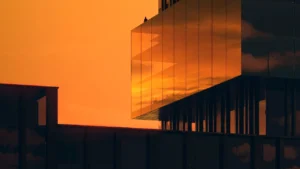 Sunset view of the glass facade at Haus of Tenet by IRTH in Business Bay, Dubai, showcasing reflective architecture, warm golden tones, and a refined modern silhouette against the evening sky, presented by Tohid Fetrat