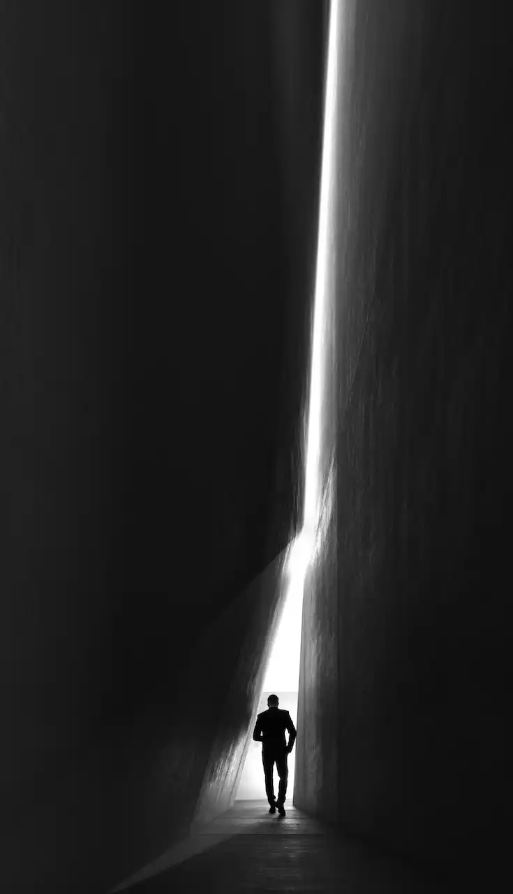 Minimalist architectural passage known as The Switch at Haus of Tenet by IRTH in Business Bay, Dubai, featuring a dramatic vertical light cut and a silhouetted figure walking toward the light, presented by Tohid Fetrat