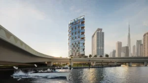 Waterfront exterior view of HQ by Rove along the canal featuring a modern tower, bridge connections, and the Dubai skyline in the background, Presented by Tohid Fetrat