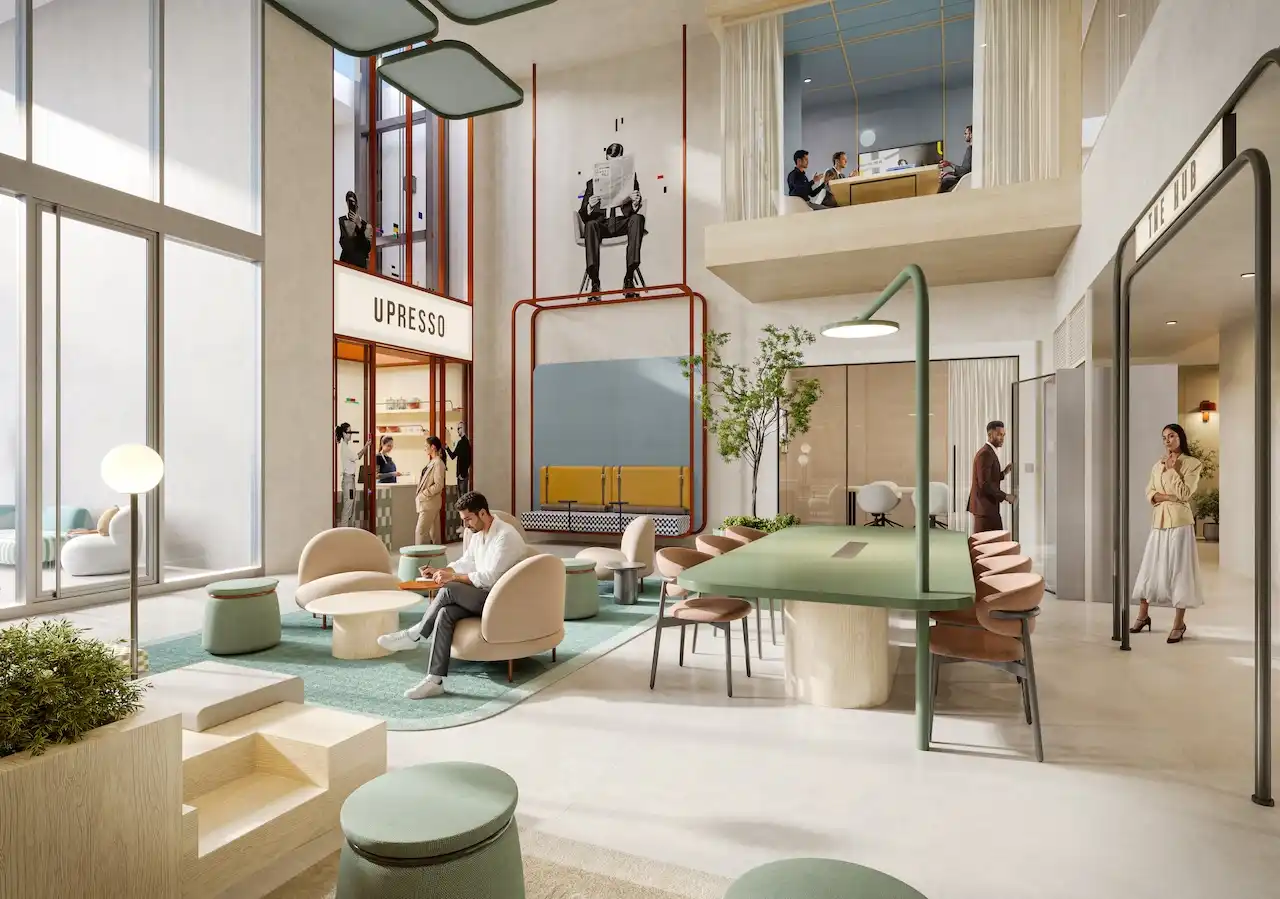 Multi level communal hub at HQ by Rove featuring lounge seating, shared tables, double height space, and integrated greenery with café frontage in Dubai, Presented by Tohid Fetrat