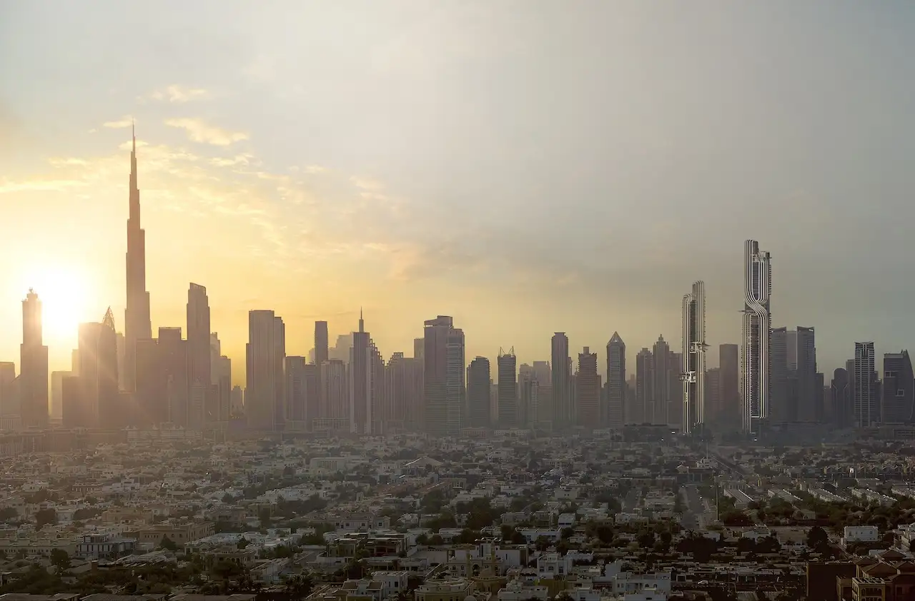 Panoramic sunset view of Dubai’s skyline featuring Burj Khalifa and the distinctive twin towers of Lumena Alta rising on the horizon. Presented by Tohid Fetrat.