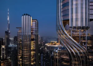 Night view of Lumena Alta twin towers featuring a sculptural sky bridge and illuminated terraces with Burj Khalifa rising in the background over Dubai’s skyline. Presented by Tohid Fetrat.