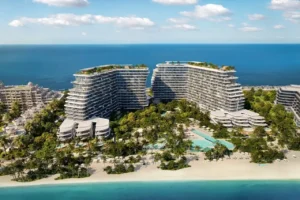 Aerial daytime view of Passo by Beyond on Palm Jumeirah, featuring twin luxury residential buildings set within lush landscaped gardens, private beachfront, resort-style swimming pools, and panoramic views of the Gulf. Presented by Tohid Fetrat.