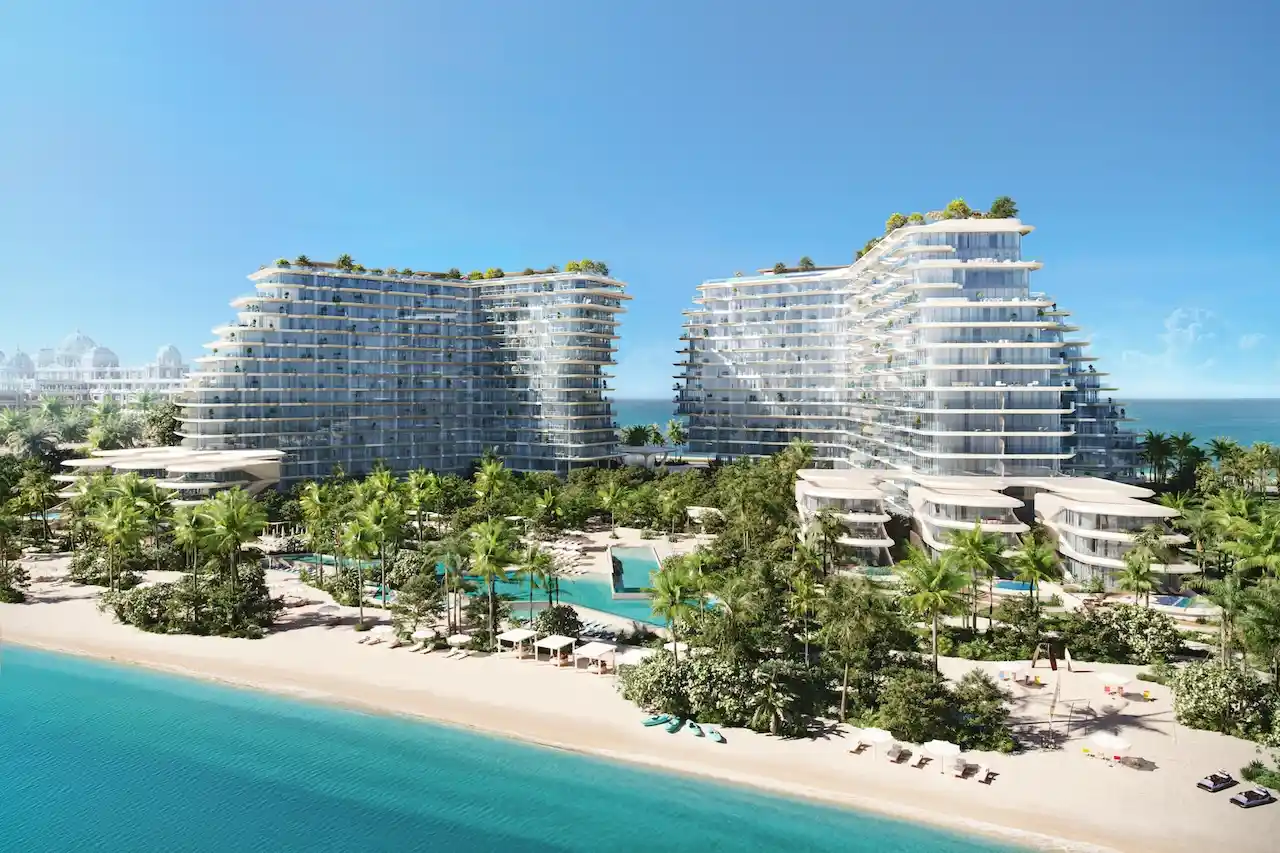 Daytime hero aerial view of Passo by Beyond on Palm Jumeirah, showcasing twin luxury beachfront residential buildings surrounded by lush tropical landscaping, private beach access, resort-style pools, and panoramic views of the Gulf. Presented by Tohid Fetrat.