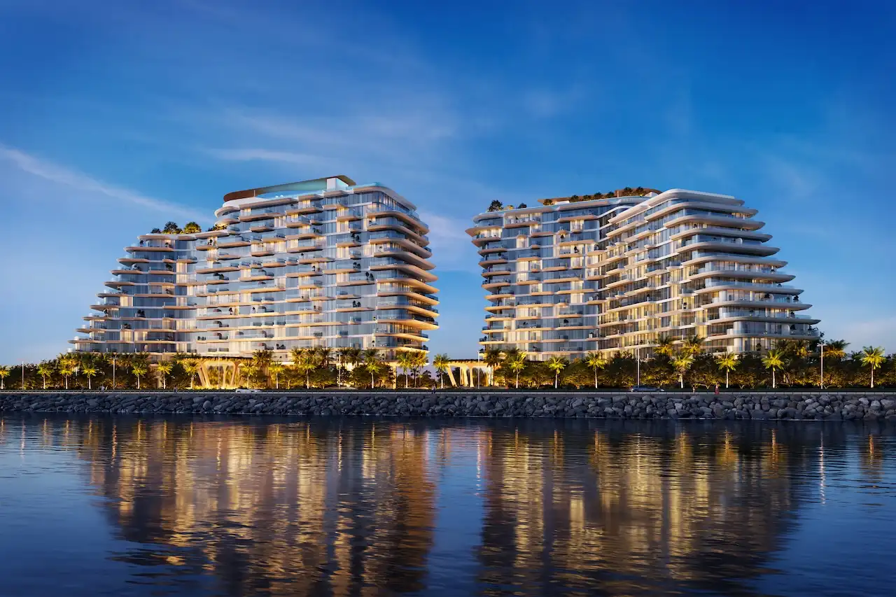Nighttime hero waterfront view of Passo by Beyond on Palm Jumeirah, featuring illuminated twin luxury residential buildings reflected on calm waters, modern beachfront architecture, and an exclusive resort-style ambiance in Dubai. Presented by Tohid Fetrat.