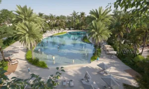 Aerial view of the lagoon-style pool at Daintree Park in Sobha Elwood, featuring tropical landscaping, palm trees, sun loungers, and shallow water zones within a master-planned residential community in Dubai, Presented by Tohid Fetrat