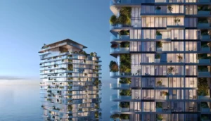 Nighttime facade view of Soulever twin residential towers illuminated with warm interior lighting, layered balconies, and integrated greenery, overlooking the Gulf in Dubai. Presented by Tohid Fetrat.