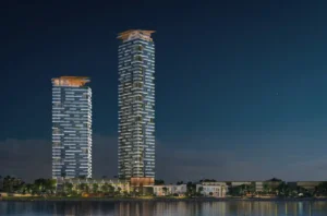 Nighttime waterfront view of Soulever twin residential towers overlooking the Gulf, illuminated with elegant lighting, sculpted balconies, and contemporary luxury architecture in Dubai. Presented by Tohid Fetrat.