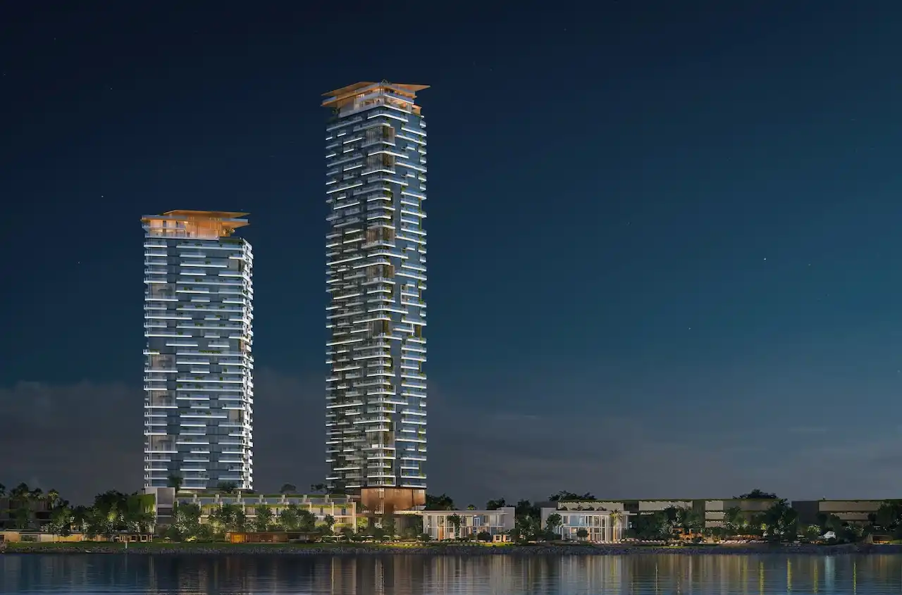 Nighttime waterfront view of Soulever twin residential towers overlooking the Gulf, illuminated with elegant lighting, sculpted balconies, and contemporary luxury architecture in Dubai. Presented by Tohid Fetrat.