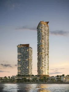 Sunset waterfront view of Soulever twin residential towers overlooking the Gulf, featuring sculpted balconies, vertical greenery, and elegant contemporary architecture in Dubai. Presented by Tohid Fetrat.