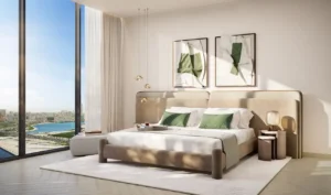Luxury three-bedroom master bedroom interior at The Edit at d3 featuring floor-to-ceiling windows, modern upholstered bed, soft neutral tones, and Dubai skyline views in Dubai Design District, Presented by Tohid Fetrat