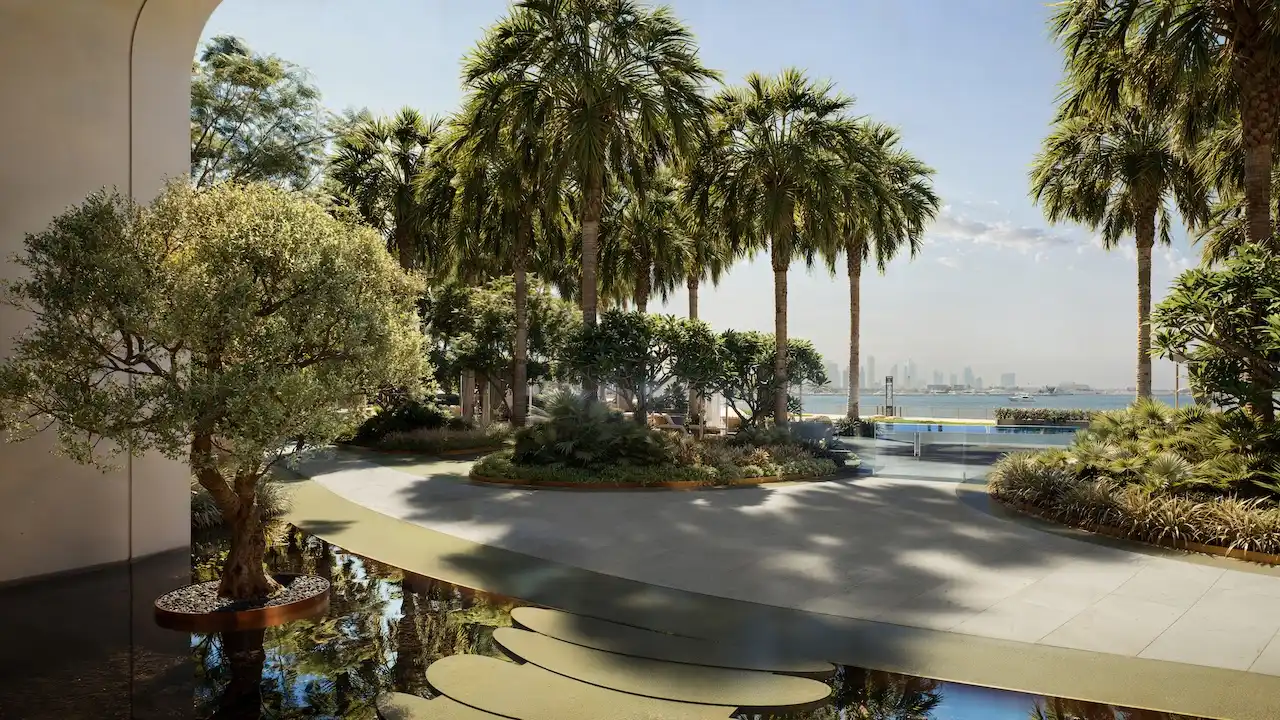 Outdoor landscaped amenity at The Edit at d3 featuring palm-lined walkways, tranquil water features, shaded seating areas, and a serene waterfront-inspired setting in Dubai Design District, Presented by Tohid Fetrat