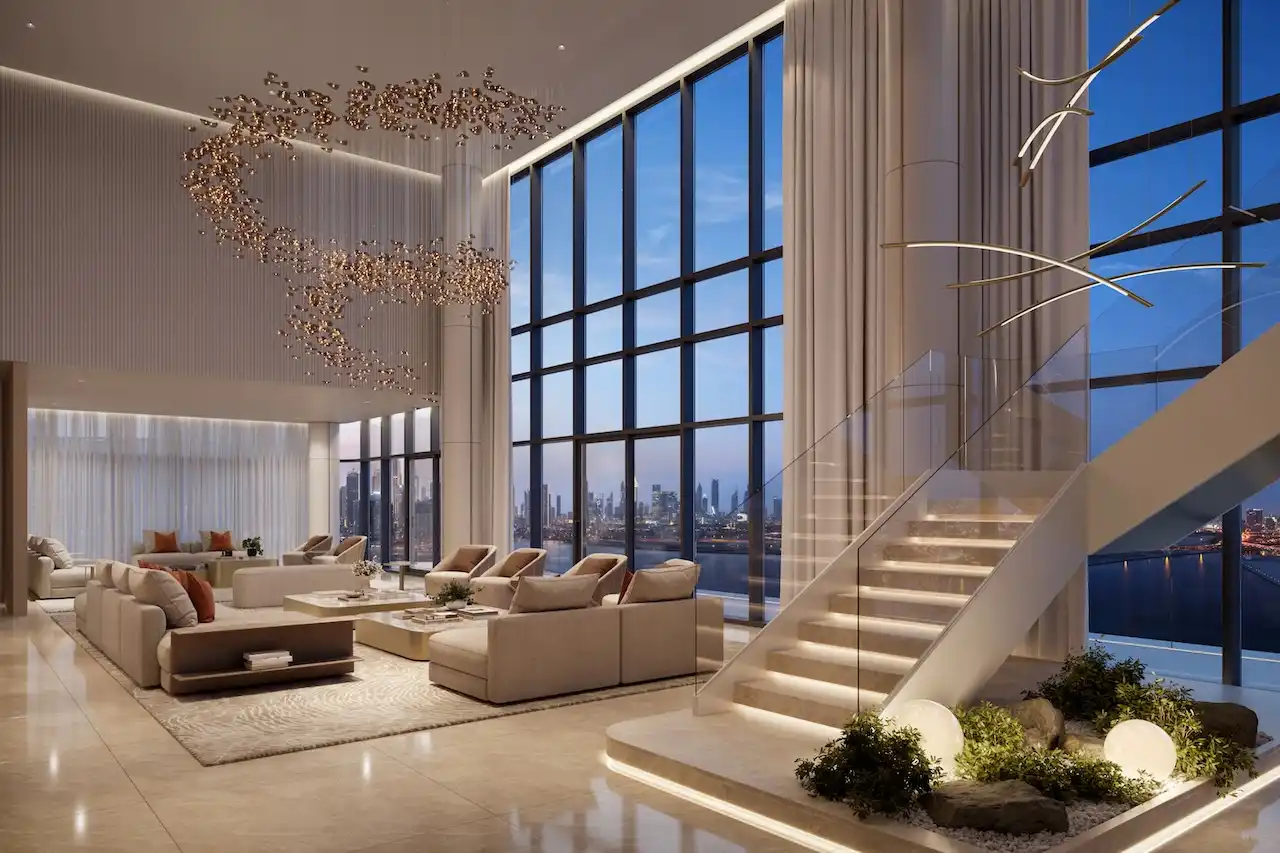 Double-height penthouse living room at The Edit at d3 featuring floor-to-ceiling glass façade, illuminated sculptural staircase, artistic chandelier installation, and panoramic Dubai skyline views, Presented by Tohid Fetrat