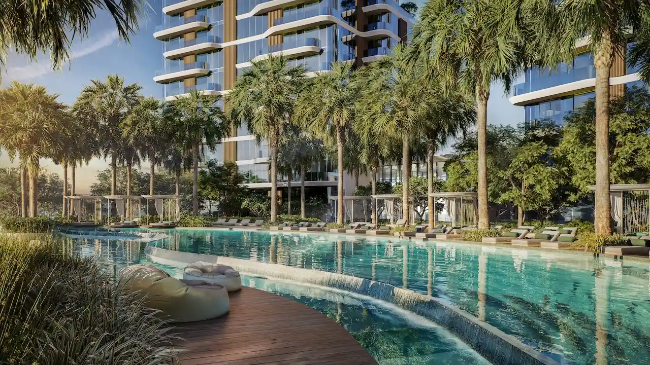 Waterfront swimming pool surrounded by palm trees and luxury residential towers at The Edit at d3 in Dubai Design District, Presented by Tohid Fetrat