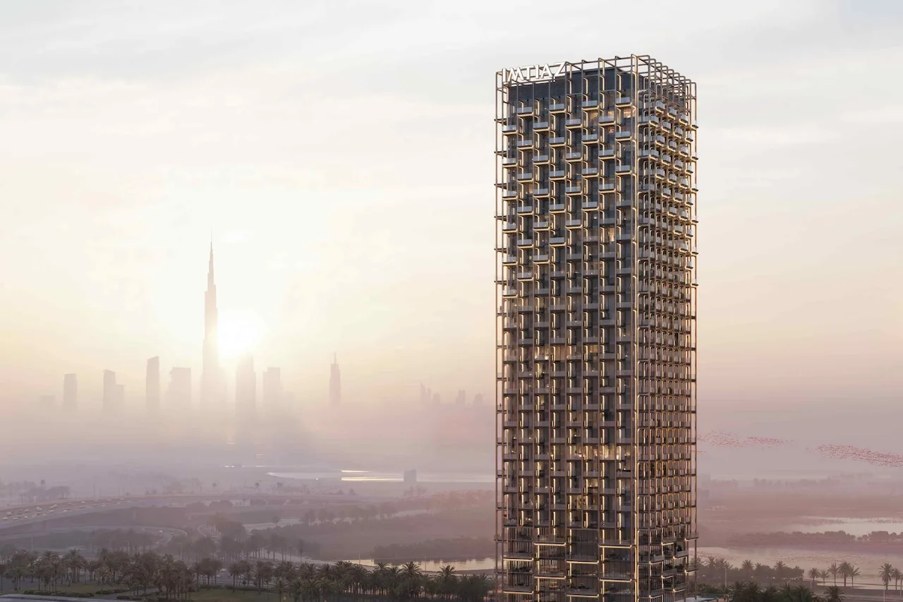Full exterior view of The Symphony Tower by Imtiaz showcasing its sculptural high-rise architecture with illuminated balconies against the Dubai skyline and Burj Khalifa at sunset, Presented by Tohid Fetrat