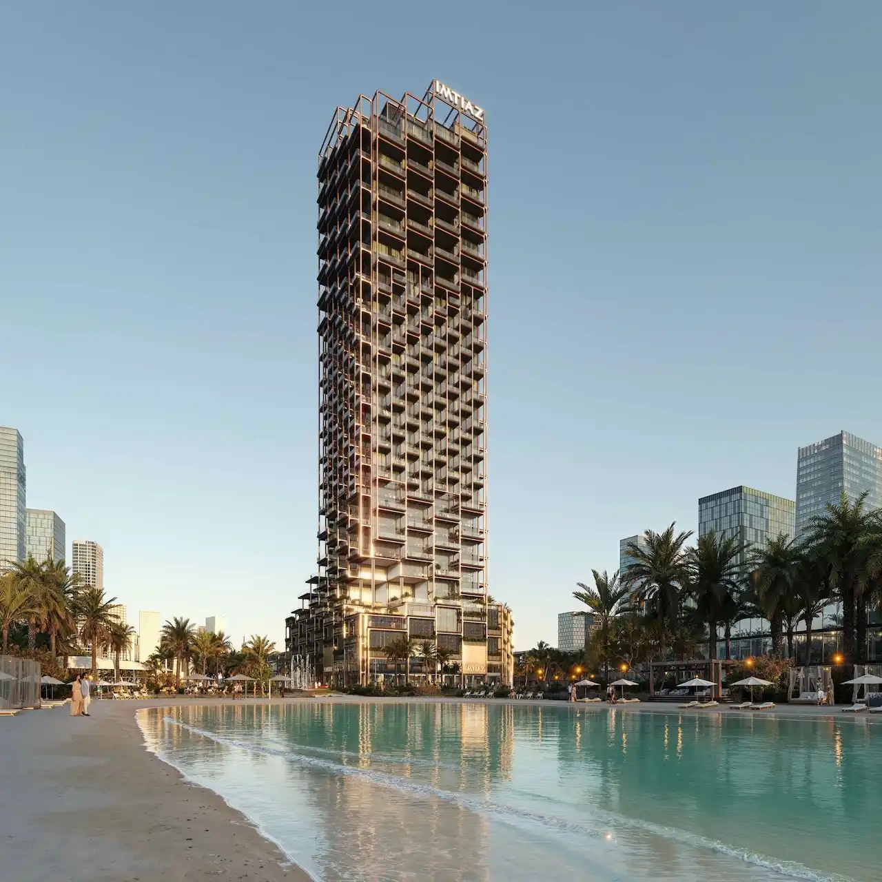 The Symphony Tower by Imtiaz overlooking a lagoon-style waterfront, featuring a modern high-rise design with illuminated balconies and palm-lined surroundings in Dubai, Presented by Tohid Fetrat