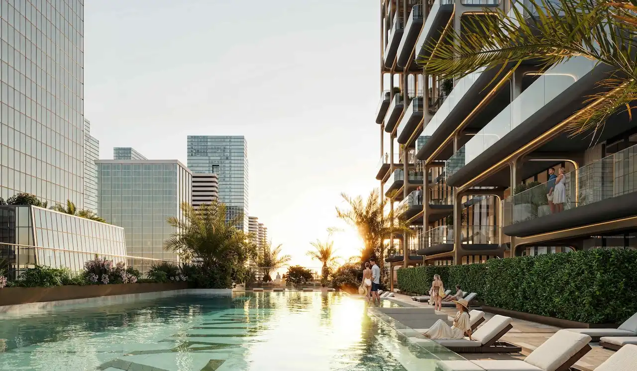 Luxury outdoor pool deck at The Symphony Tower by Imtiaz featuring resort-style swimming pool, sun loungers, landscaped greenery, and modern residential architecture in Dubai, Presented by Tohid Fetrat