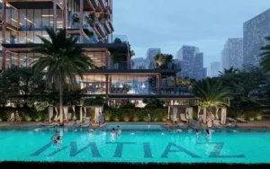Evening view of The Symphony Tower by Imtiaz featuring the illuminated podium swimming pool, landscaped cabanas, palm-lined deck, and stepped glass terraces with Dubai’s skyline in the background, Presented by Tohid Fetrat