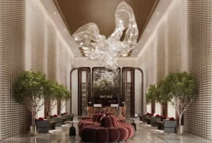 Luxury residential lobby at The Symphony Tower by Imtiaz featuring a dramatic sculptural glass chandelier, elegant seating, indoor trees, refined materials, and a grand reception area with contemporary design, Presented by Tohid Fetrat