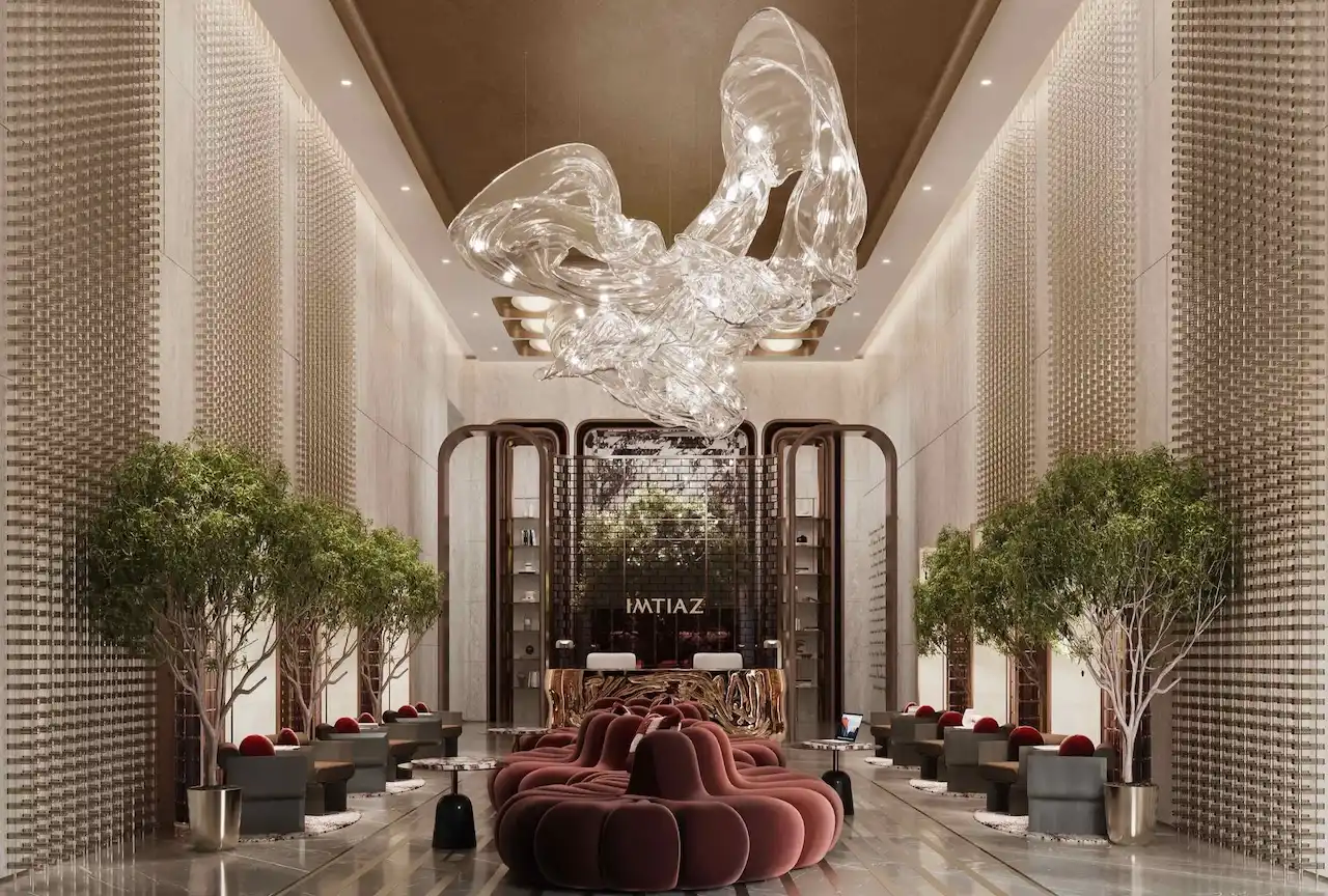 Luxury residential lobby at The Symphony Tower by Imtiaz featuring a dramatic sculptural glass chandelier, elegant seating, indoor trees, refined materials, and a grand reception area with contemporary design, Presented by Tohid Fetrat