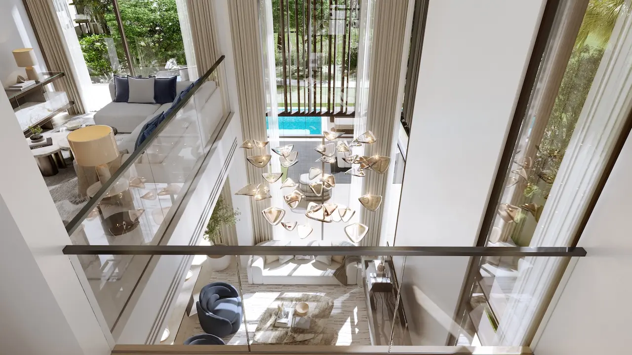 Double height living space of a five bedroom villa at Nad Al Sheba Gardens Phase 11 with designer chandelier, glass balustrade and garden view Presented by Tohid Fetrat