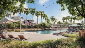 Poolside leisure area at Nad Al Sheba Gardens Phase 11 with sun loungers, palm trees, landscaped greenery and contemporary villas under a clear Dubai sky Presented by Tohid Fetrat