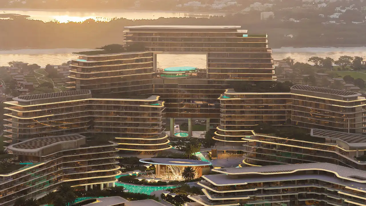 Sunset view of The Meriva Collection by Ellington showcasing illuminated facades, layered architecture and central leisure deck in Dubai Presented by Tohid Fetrat