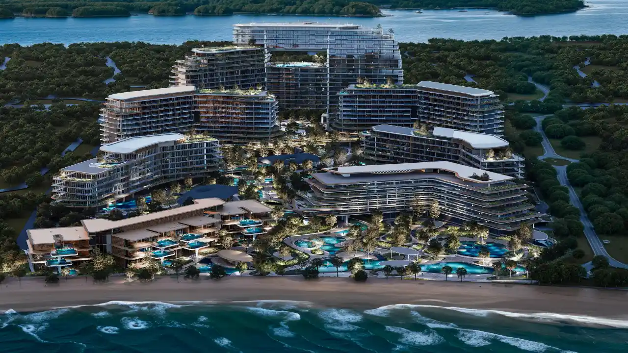 Evening aerial view of The Meriva Collection by Ellington displaying beachfront architecture, illuminated lagoon pools and landscaped coastal amenities in Dubai Presented by Tohid Fetrat