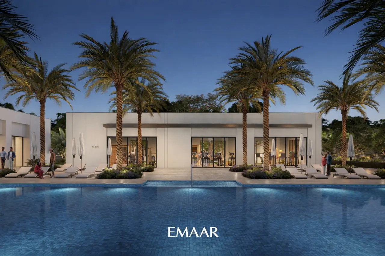 Evening view of The Valley by Emaar community clubhouse with swimming pool palm trees sun loungers and modern leisure facilities in Dubai Presented by Tohid Fetrat