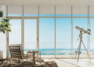 Beach Vista at Emaar Beachfront by Emaar lounge area with armchair telescope and panoramic sea view through floor to ceiling windows in Dubai - Presented by Tohid Fetrat