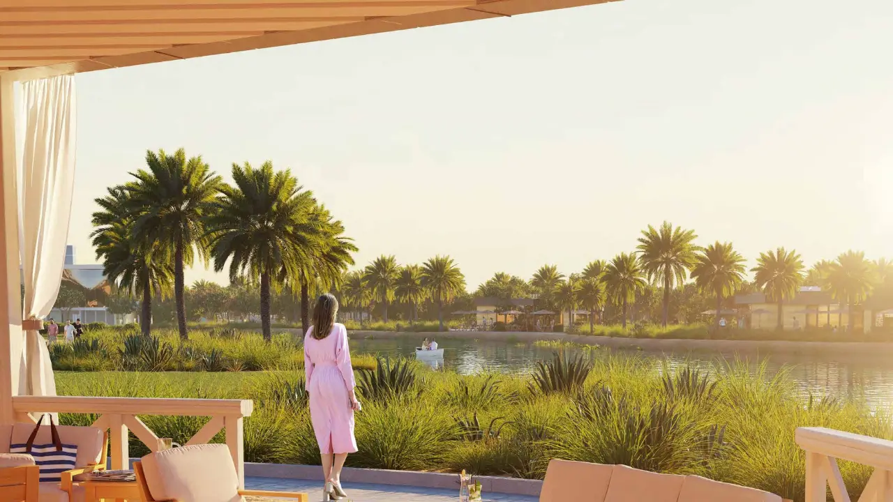 DAMAC Hills 2 by DAMAC Properties lagoon view with palm trees landscaped greenery and terrace seating area in Dubai - Presented by Tohid Fetrat