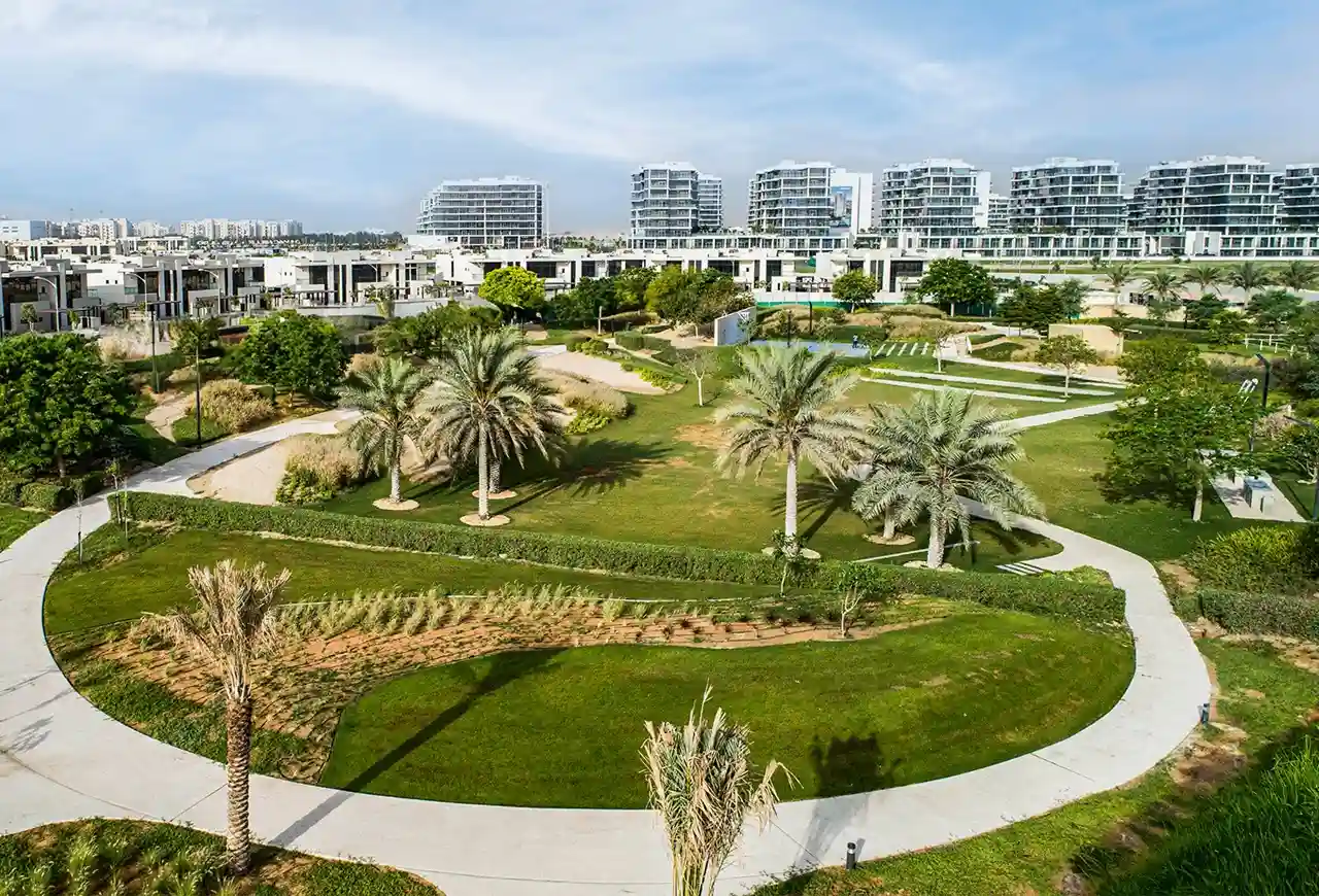 DAMAC Hills landscaped community park with walking paths green lawns palm trees and residential buildings in Dubai Presented by Tohid Fetrat