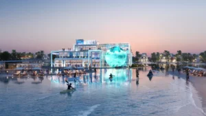 DAMAC Islands by DAMAC Properties lagoon clubhouse with illuminated glass facade waterfront seating and leisure activities at sunset in Dubai - Presented by Tohid Fetrat